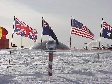 Photo of Ceremonial marker at the South Pole, including flags of the original signatory nations of the Antarctic Treaty.